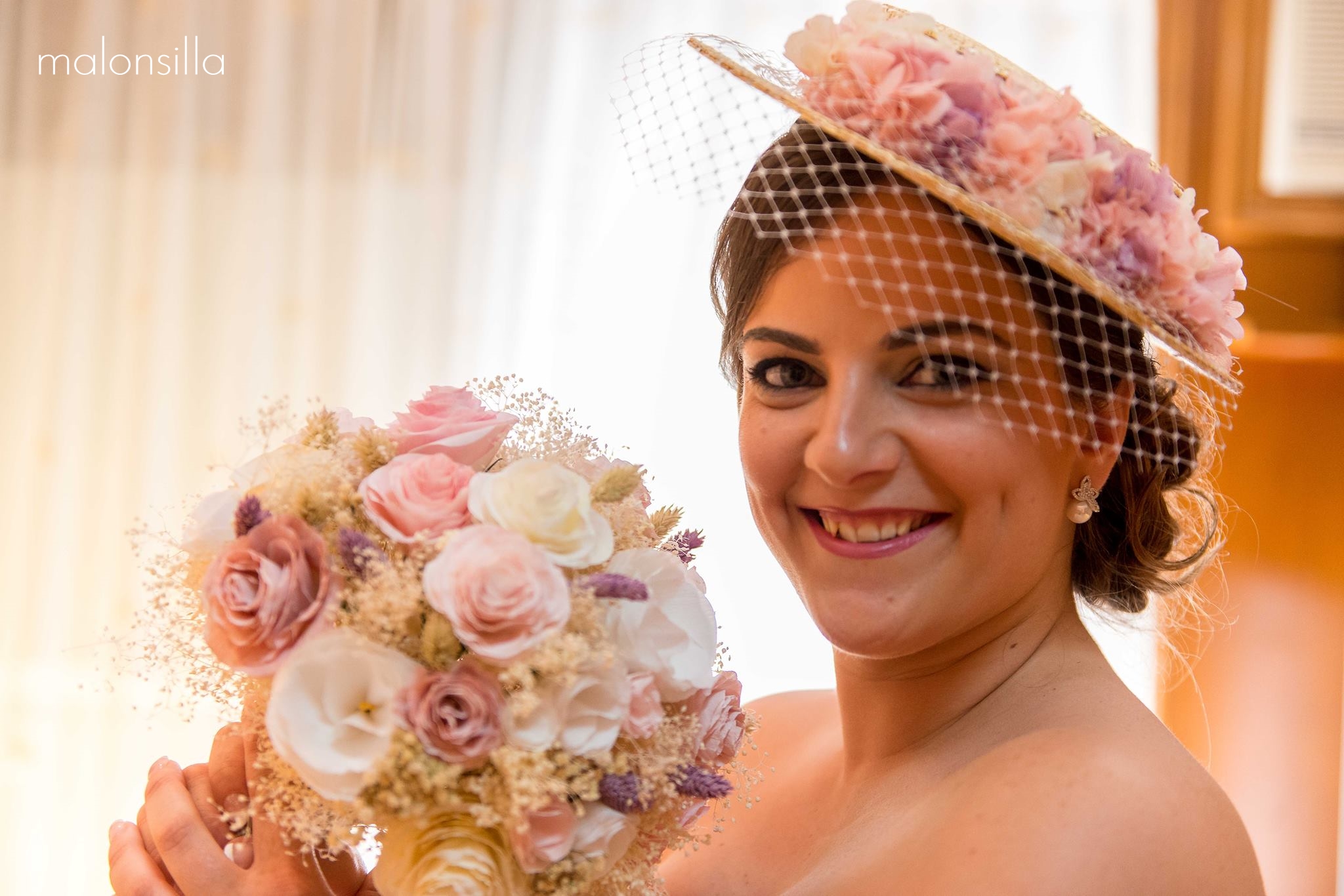 Novia con canotier y ramo en tono rosa pálido con vestido palabra de honor